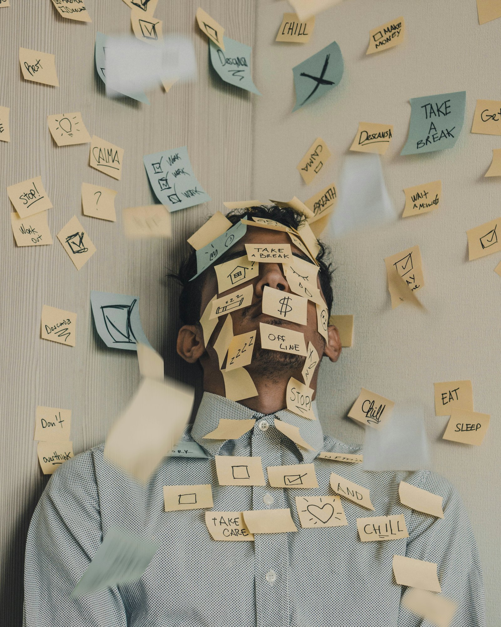 A person at a desk covered in sticky notes, overwhelmed by tasks